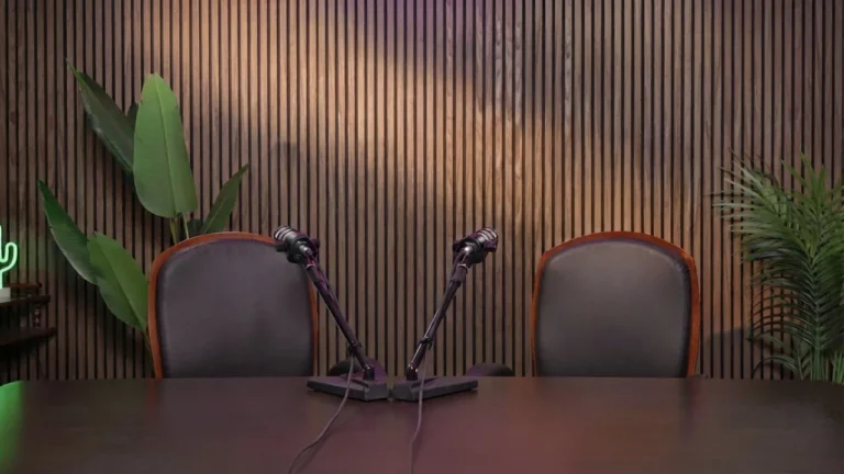 Allestimento essenziale dello studio Podbox: due poltrone, due microfoni e parete in listelli di legno