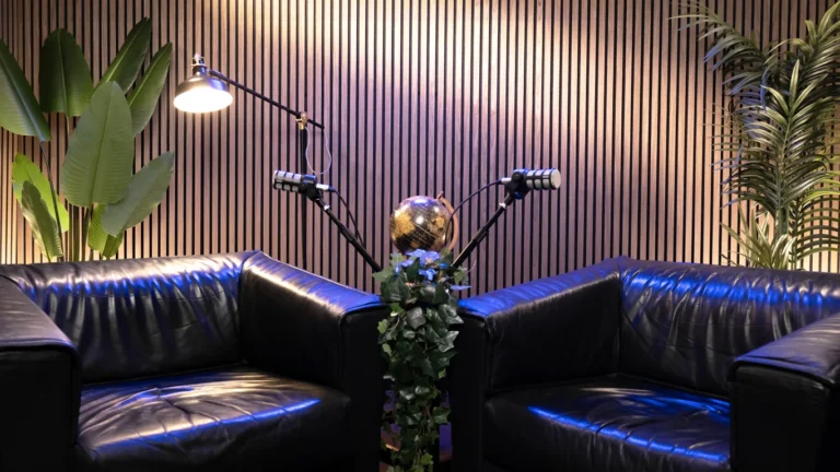 Allestimento salotto con divani in pelle, luce blu e due microfoni nello studio Podbox